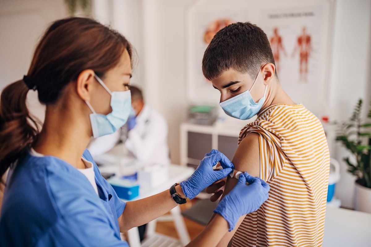 Latina child and her mother at a health fair. The girl is sticking out her tongue to get a test from a doctor with white hair.