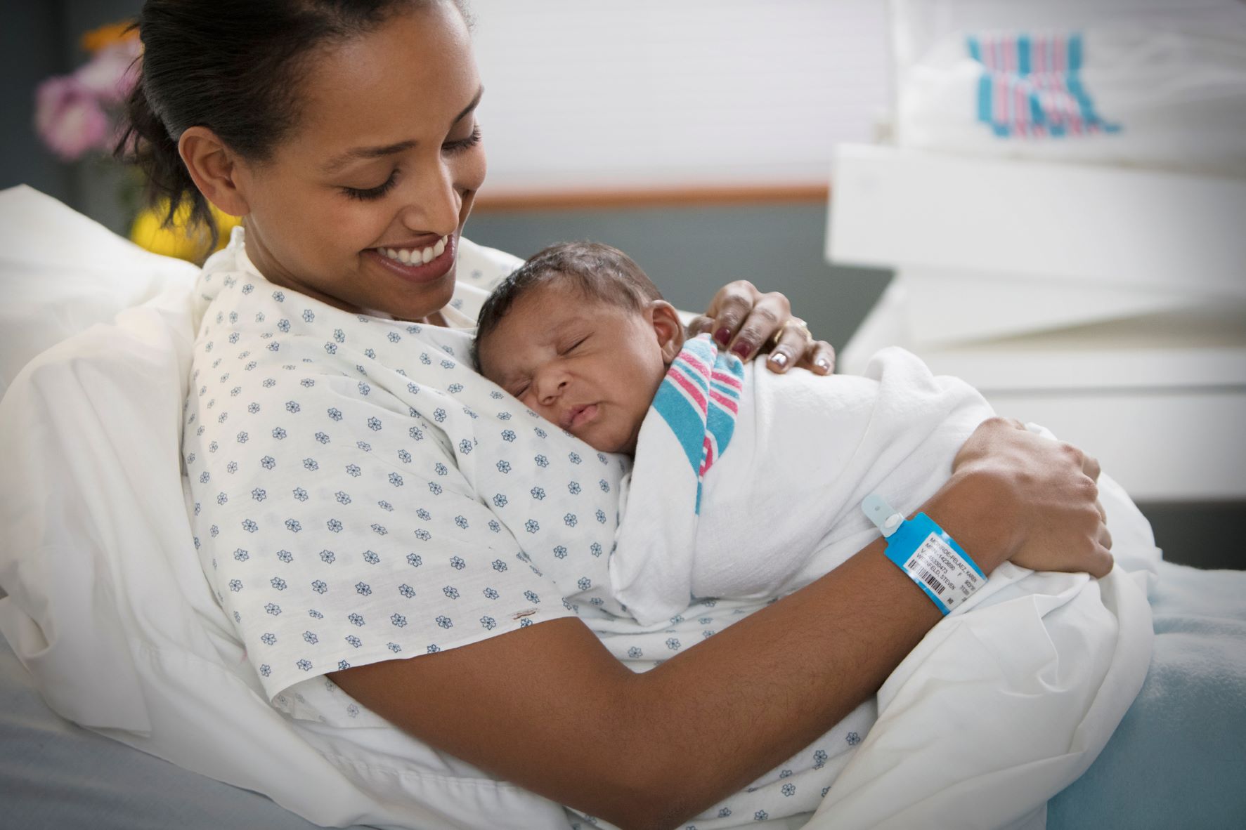 Image of a person holding a newborn baby in a hospital bed