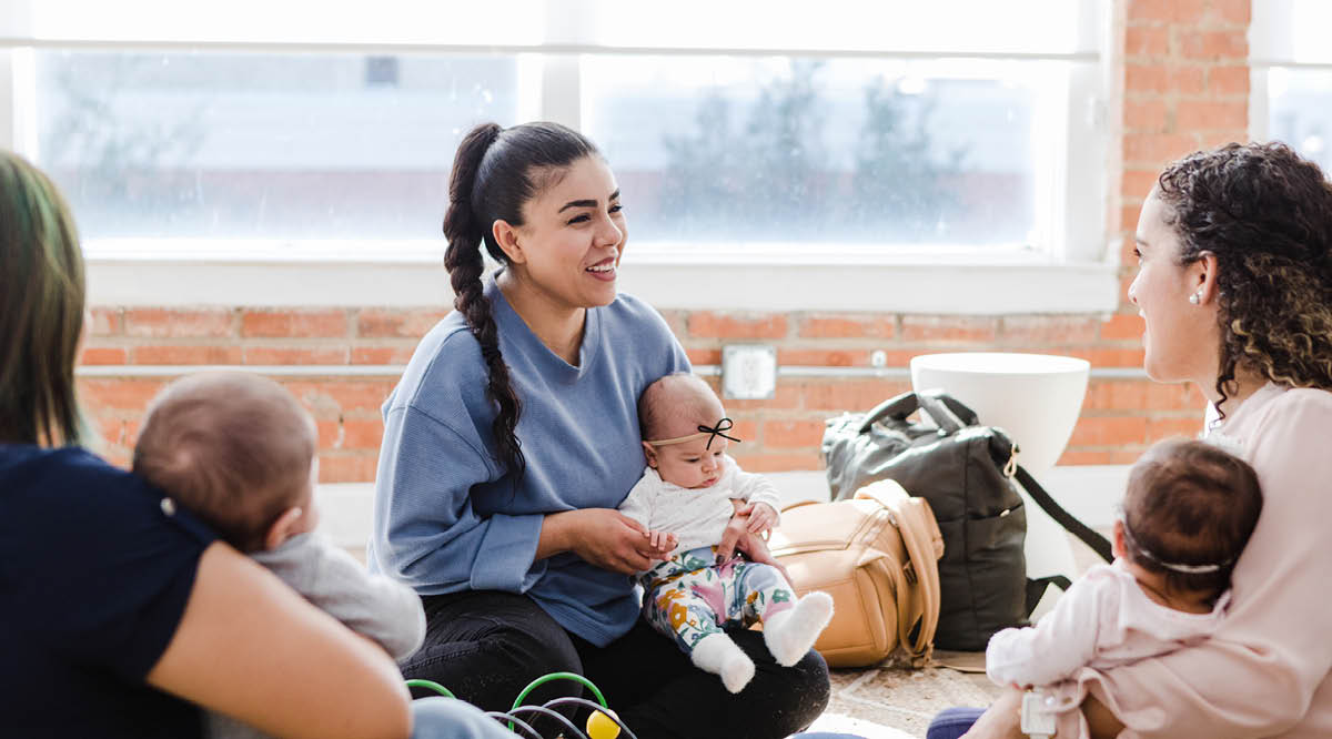 New moms chat while holding their babies