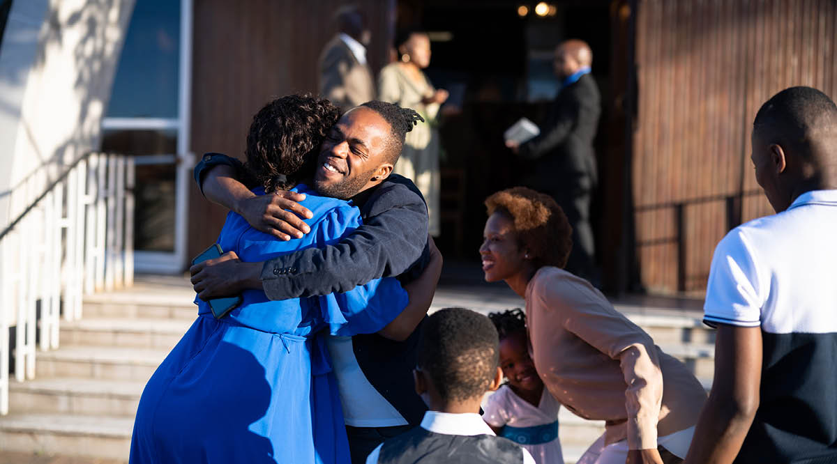 People greet each other warmly outside a church