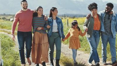 Five diverse adults and one child walk side by side through a field.