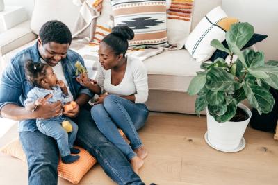 Happy Black mother and father with their small child playing on the floor with blocks and a stuffed toy.