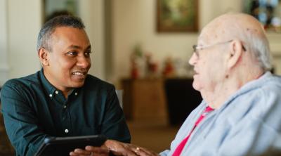 Revised Principles Landing Page A caregiver holds the hand of an older man he's listening to.