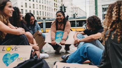 AAMC News EJ Viewpoint 1345174224 A group of students sit outdoors holding posters after an environmental justice protest.
