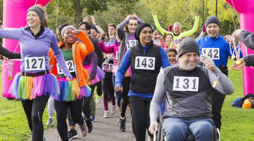 A large, diverse, group of people finishes a race together and celebrate their accomplishment.
