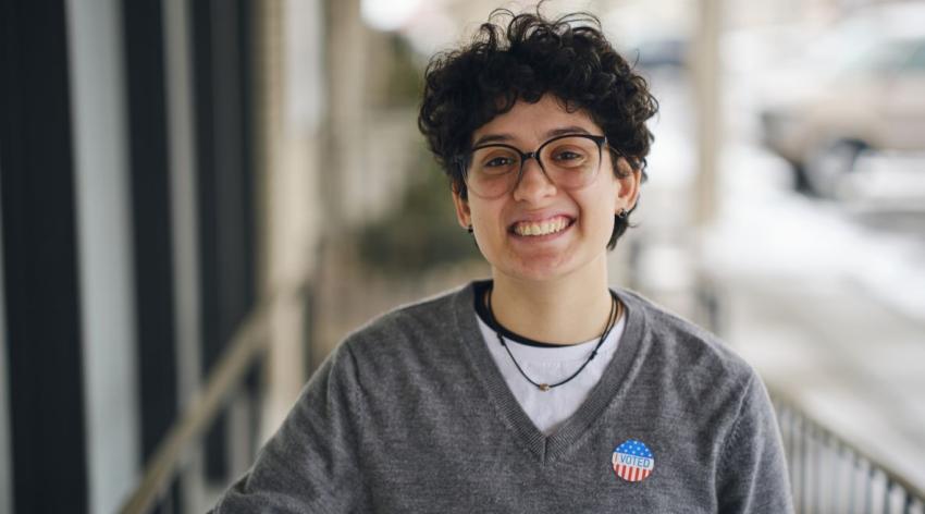 Smiling young Hispanic person wearing an "I Voted" sticker