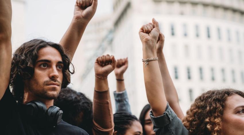 Young people raising their fists in solidarity at a protest.