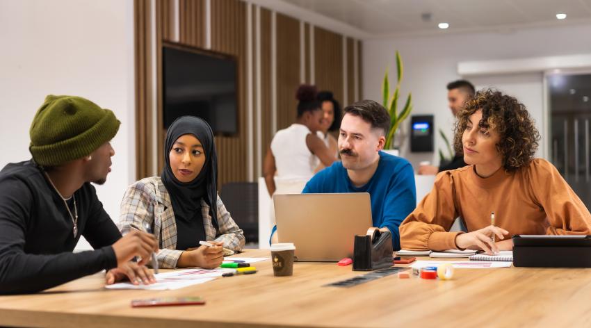 Workers talking at common coworking space tables, busy multiethnic businessmen and businesswomen working together in the space of coworking, diverse staff of employees