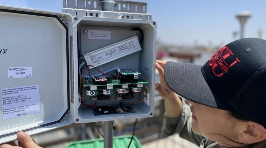 A person checks a community air monitoring station in San Ysidro.