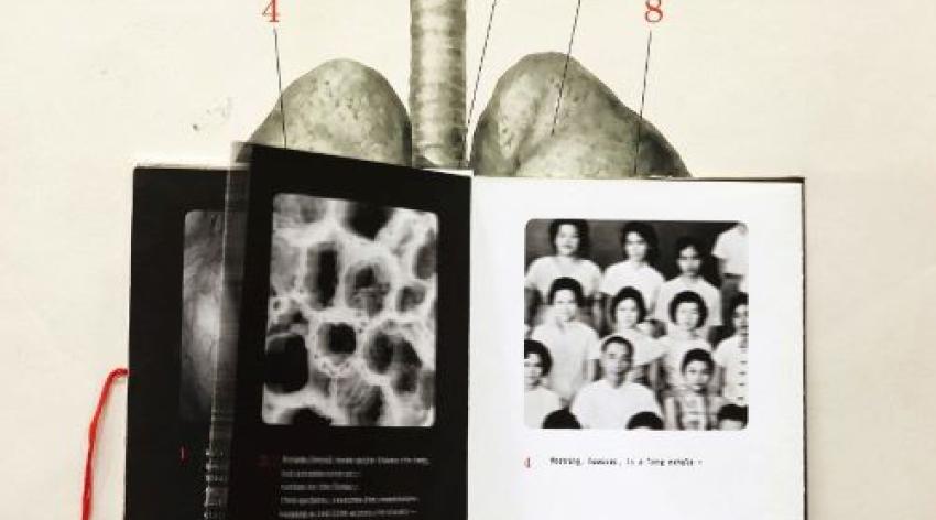 Art piece from Silent Anatomies. A hand holds up a book of old photos of people and microscope slide in front of a medical illustration of lungs labeled Metal Lungs and some Chinese calligraphy. 