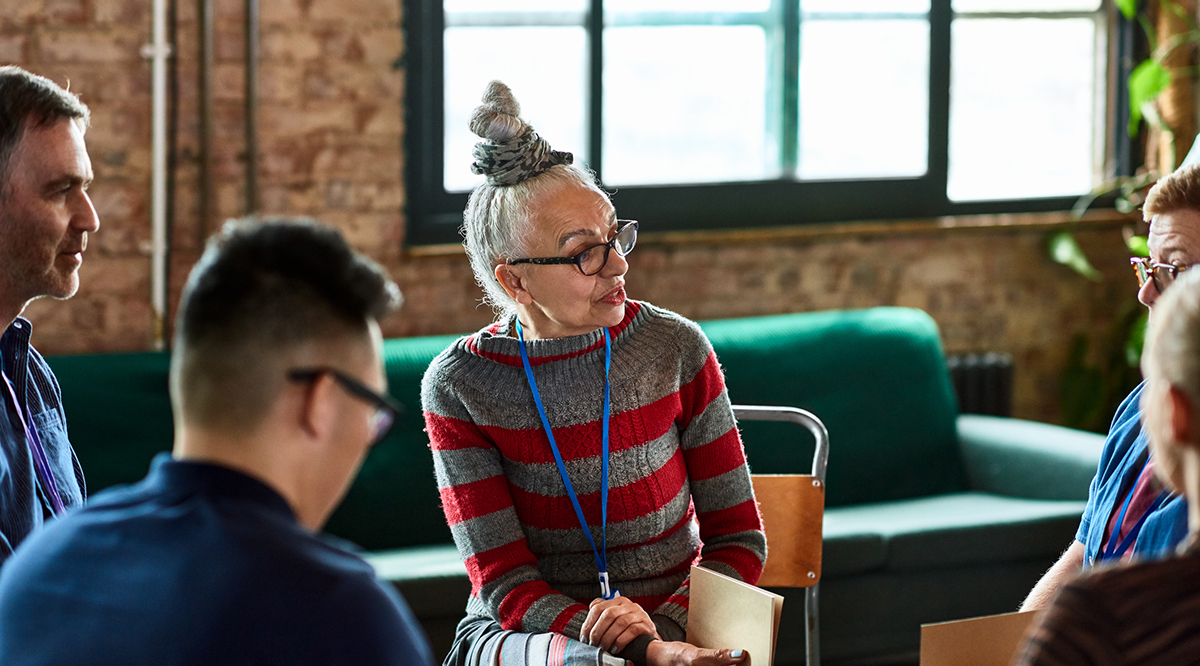 Senior woman talking to small group in office training session